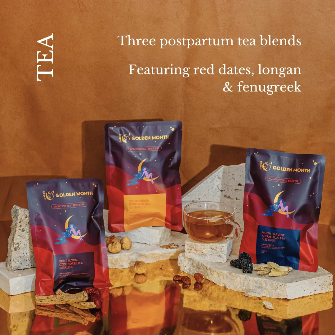 Three packages of Golden Month tea with a glass of tea on a stone surface, against a warm brown background.